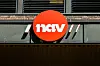 Rund rød NAV-logo montert på fasade ved Tøyen torg i Oslo
