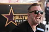 Ricky Gervais smilende ved sin stjerne på Hollywood Walk of Fame under et intervju.