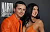 Timothée Chalamet og Kylie Jenner i oransje antrekk på premierefotovegg for «Marty Supreme».