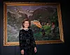 Dronning Sonja poserer foran et stort landskapsmaleri av Nikolai Astrup i en galleriutstilling.