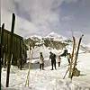 Skiløpere smører ski utenfor Gjendebu omgitt av snø og fjell i Jotunheimen i 1963.
