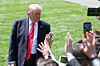 President Donald Trump stands on the White House South Lawn as reporters reach up while waiting to ask questions.