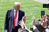 President Donald Trump stands on the White House South Lawn as reporters reach up while waiting to ask questions.