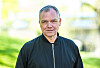 Portrett av Arne Lygre utendørs foran en lys, grønn bakgrunn.