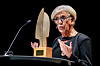 Hilde Henriksen Waage står på en scene med mikrofon og prisstatuett under utdelingen av Fritt Ords pris.
