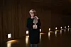 Hilde Henriksen Waage står i en mørk sal og holder Fritt Ords Pris, med lys i veggen bak.