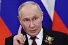 Vladimir Putin peker mens han taler foran russiske flagg i Det store Kreml-palasset.