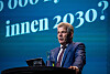 Bjørnar Skjæran taler fra en talerstol foran en blå konferansebakgrunn.