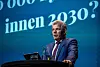 Bjørnar Skjæran taler fra en talerstol foran en blå konferansebakgrunn.