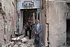 Zaradasht Ahmed står foran en ødelagt bygning med ruiner og en skadet døråpning i Mosul.