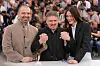Tre personer poserer med sammenknyttede hender ved et fotoopptak på Cannes-festivalen.