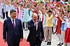 Vladimir Putin og Xi Jinping går på rød løper under en velkomstseremoni i Beijing med barn som vifter med flagg.