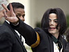 Michael Jackson vinker med hånden mens han ankommer en rettsbygning, med en sikkerhetsvakt ved siden av seg.