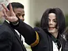 Michael Jackson vinker med hånden mens han ankommer en rettsbygning, med en sikkerhetsvakt ved siden av seg.