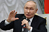 Vladimir Putin holder en mikrofon og hever den andre hånden under et møte i Kreml i Moskva.