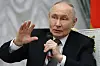 Vladimir Putin holder en mikrofon og hever den andre hånden under et møte i Kreml i Moskva.