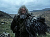 Hugh Jackman som Robin Hood står i mørke klær i et barskt fjellandskap.