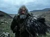 Hugh Jackman som Robin Hood står i mørke klær i et barskt fjellandskap.