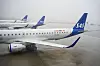SAS-passasjerfly står på våt rullebane på Gardermoen med flere fly i bakgrunnen.