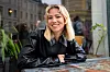 Dagny sitter ved et bord utendørs i Oslo og smiler mot kamera.