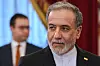 Abbas Araghchi i mørk dress ankommer et møte i St. Petersburg med en mann i bakgrunnen.