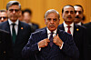 Shehbaz Sharif justerer slipset foran to menn under ankomst til møte i Beijing.
