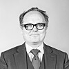 Sort-hvitt portrett av en Finn Iunker foran lys bakgrunn.