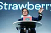 Petter Stordalen smiler og vinker fra en talerstol foran en Strawberry-bakgrunn.