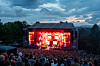 Publikum foran en rødlyst hovedscene på Øyafestivalen i Oslo ved skumring.