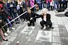 Liv Ullmann og Jakob Oftebro kneeler ved to inngravde plater i en gågate omgitt av publikum.
