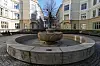 Fontene med bronseskulptur i en gårdsplass omgitt av lyse bygårder i Oslo.