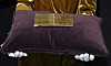 Bonhams-ansatt viser en gullbillett fra «Willy Wonka & The Chocolate Factory» på en lilla pute.
