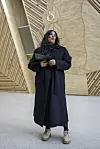 Kulturminister Lubna Jaffery står foran et stort veggkunstverk i et lyst rom med trekledde vegger.