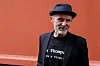 Jo Nesbø står foran en rød vegg under ankomst til Aschehougs hagefest i Oslo.