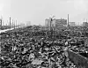 Svarthvitt bilde av ruinene i Hiroshima etter atombomben, med ødelagte bygninger og sønderrevet terreng.