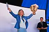 Sylvi Listhaug løfter en pokal på en scene, mens Lars Barstad Løvold står i bakgrunnen.