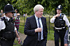Charles Spencer går utendørs mellom politibetjenter ved Kensington Palace i London.
