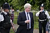 Charles Spencer går utendørs mellom politibetjenter ved Kensington Palace i London.