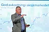 Nicolai Tangen står foran en skjerm med graf og teksten «God avkastning i aksjemarkedet».