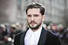 Kit Harington i svart smokingjakke poserer foran fotografer i London.