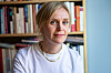 Kjersti Annesdatter Skomsvold i hvit skjorte foran en bokhylle.