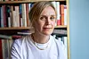 Kjersti Annesdatter Skomsvold i hvit skjorte foran en bokhylle.