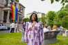 Lubna Jaffery i fargerik kjole i en hage med regnbueflagg under Oslo Pride.