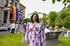Lubna Jaffery i fargerik kjole i en hage med regnbueflagg under Oslo Pride.