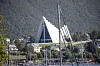Ishavskatedralen i Tromsø ved vannet, med fjell, bebyggelse og båter i forgrunnen