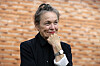 Laurie Anderson poserer i svart antrekk foran en murvegg i Milano.