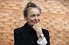 Laurie Anderson poserer i svart antrekk foran en murvegg i Milano.