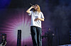 Girl in red synger i mikrofon på en opplyst festivalscene, med en keyboardspiller bak seg.