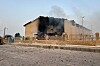 Mørk røyk stiger fra en skadet bygning bak et gjerde i Lamerd, Iran.