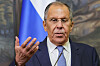 Sergey Lavrov taler foran et russisk flagg og løfter hånden under en pressekonferanse.